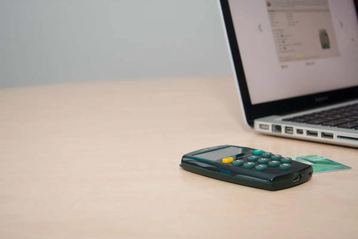 Credit card beside a calculator and laptop on a desk for managing personal finances.