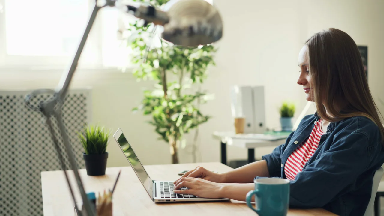 Office worker sitting at a desk and working on a laptop.
