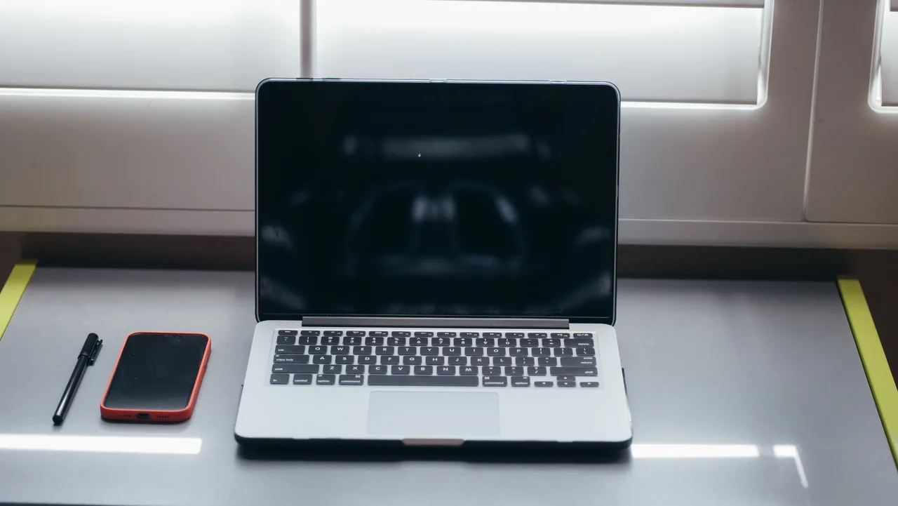 Minimalist workspace with a laptop and smartphone on a clean desk.